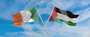 two crossed flags Palestine and Ireland waving in wind at cloudy sky. Concept of relationship, dialog, travelling between two