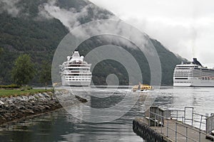 Two cruise ships are moored in a fjord in Norway and are waiting for passengers to disembark with dinghies