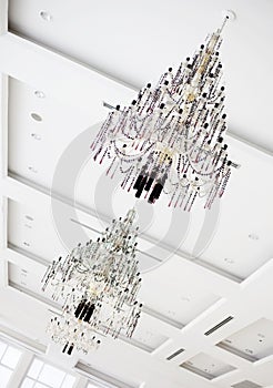 Two crystal chandeliers hanging on white ceiling