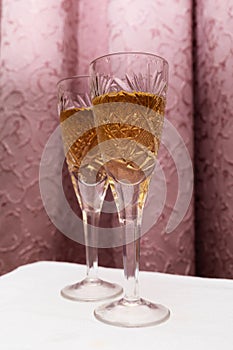 Two crystal glasses with champagne on a curtain background, concept in the nineties style