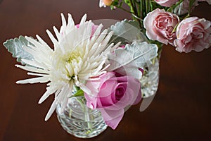 Two crystal vases with flowers on dark wood table