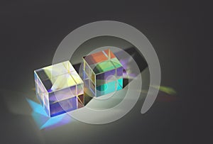 Two cubic glass prism refract light into different colors and cast shadows photo
