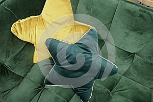 Two cuddly yellow star-shaped pillow on a green sofa