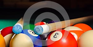 Two cues lie on a triangle with billiard balls on the pool table