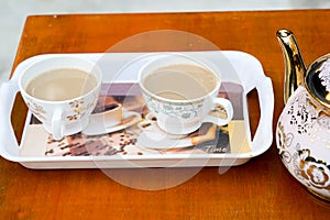 Two cup of coffee on a tray on red table.