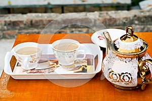 Two cup of coffee on a tray on red table.