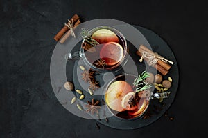 Two cups of Christmas mulled wine or gluhwein with spices and lemon slices on dark wooden background. Christmas or New Year