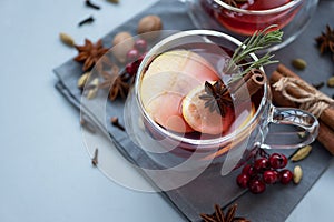Two cups of Christmas mulled wine or gluhwein with spices and lemon slices on gray wooden background. Christmas or New Year