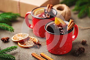 Two cups of christmas mulled wine or gluhwein with spices and orange slices on rustic table top view. Traditional drink on winter