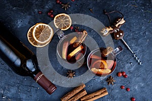 Two cups of christmas mulled wine or gluhwein with spices and orange slices on rustic table top view. Traditional drink on winter