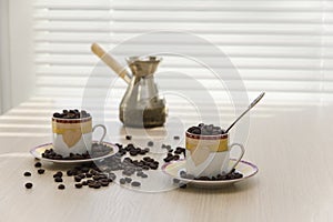 Two cups and coffee beans on the table.