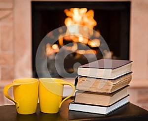 Two cups of coffee with books on the background of the fireplace