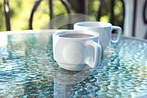 Two cups of coffee on a glass table on an open terrace