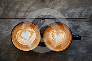Two cups of coffee with heart latte art, date concept. Valentine's day or coffee lovers. Couple of cappuccino cups on wooden
