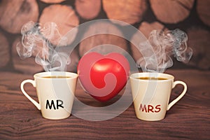 Two cups of coffee with a heart shape on a wooden background.