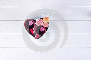 Two cups of coffee, macaroons with flowers in a box in the form of a heart on a white background. Valentine`s day