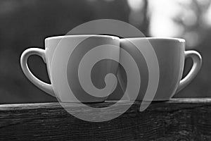 Two cups of coffee on wooden balcony on the background of sunset with beautiful bokeh lights