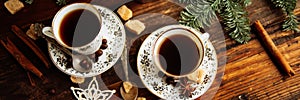 Two cups of espresso with pieces of cane sugar and Italian coffee maker on wooden table.