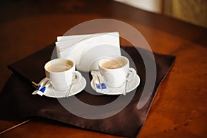 Two cups of espresso on rustic wooden table. Napkins , sugar, spoons on a table