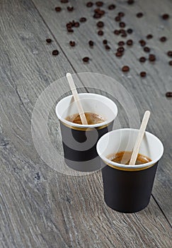 Two cups of espresso on a wooden background with coffee beans. Environmentally friendly material. Close up.