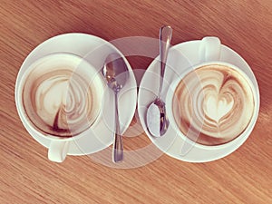 Two cups of flat white coffee on wooden table