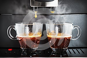 Two cups of freshly brewed coffee in the coffee machine