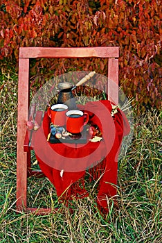 Two cups of freshly brewed coffee on an old wooden chair in nature in the autumn.