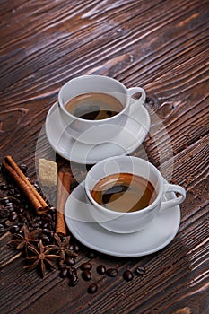 Two cups of freshly brewed espresso coffee with coffee beans on a rustic wooden table