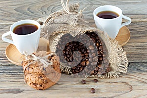 Two cups of freshly brewed espresso on wooden table. coffee beans and crunchie cookies on light wooden table  rustic style 