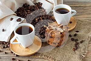 Two cups of freshly brewed espresso on wooden table. coffee beans and crunchie cookies on light wooden table, rustic style,