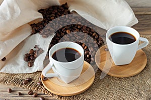Two cups of freshly brewed espresso on wooden table. coffee beans on light wooden table  rustic style  homemade