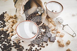 Two cups of freshly brewed, frothy cappuccino. Spilled coffee grains, chocolate and cane sugar.