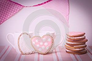 Two cups and heart cookies on pink