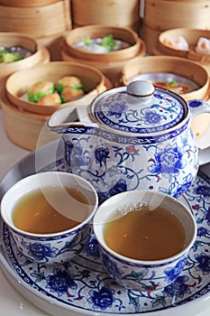 Two Cups of Hot Chinese Oolong Tea with Assorted Dim Sum Dishes in Background