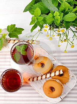 Two cups of hot tea with delicious cookies on white wooden table