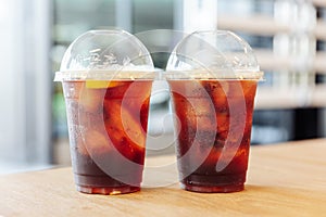 Two cups of Iced nitro cold brew coffee with lemon on wooden table with blur background