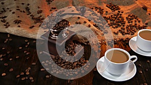 Two cups with latte on table strewn with coffee beans