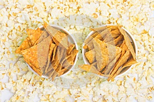Two cups of nachos on a background of popcorn top view