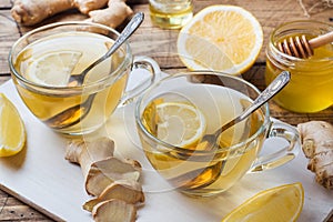 Two cups of natural herbal tea ginger lemon and honey on a wooden background