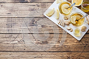 Two cups of natural herbal tea ginger lemon and honey on a wooden background. Copy space