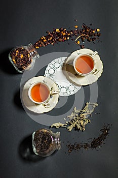 Two cups of tea on the black background with disperse tea