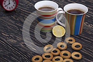 Two cups for tea with fragrant bagels on wooden background