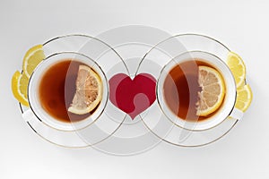 Two cups of tea with lemon and red heart on white background. The concept of relationship, happy couple in love