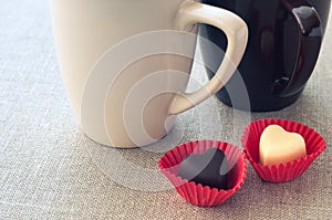 Two cups and two heart-shaped chocolates