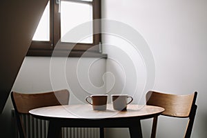 Two cups on wooden table. Dining room with table and two chairs. Modern minimal Scandinavian nordic interior. Morning coffee