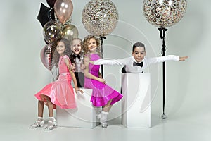 two curly-haired girls and two boys engaged in ballroom dancing, laughing and mischievously posing in a photo studio