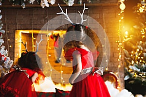 Two curly little girls looking at the christmas fireplace near b