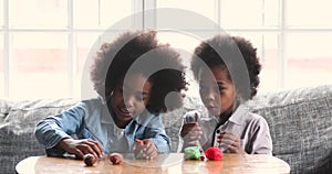 Two cute african children playing with playdough at home