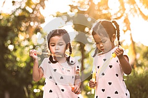 Two cute asian child girls having fun to play with bubbles