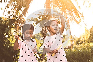 Two cute asian child girls having fun to play with bubbles